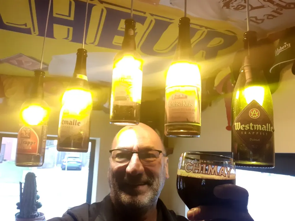 Danny Cannaerts met een glas trappist onder een rij flessenlampen