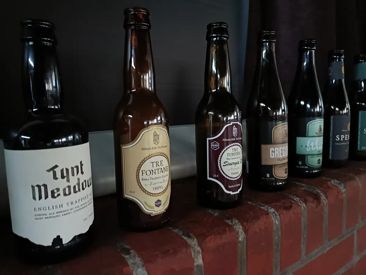 Een rij bierflessen op een bakstenen muurtje